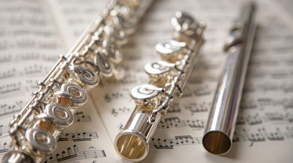 une flûte traversière démontée et posée sur une partition